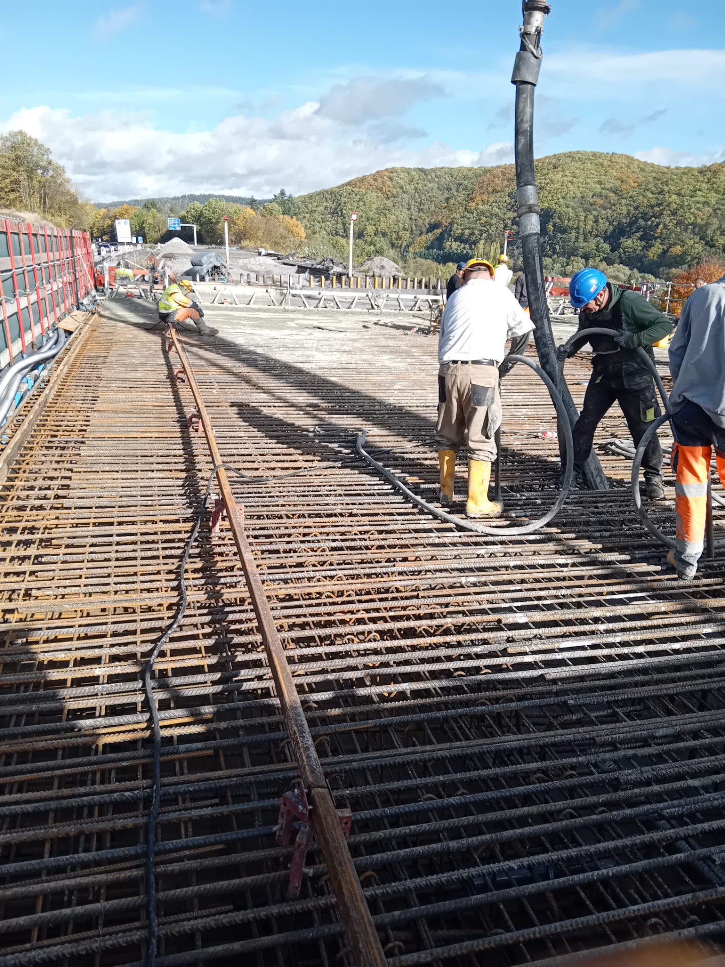 Bauarbeiter bei der Betonage einer Brückendecke mit Betonpumpe über fertig verlegter Bewehrung