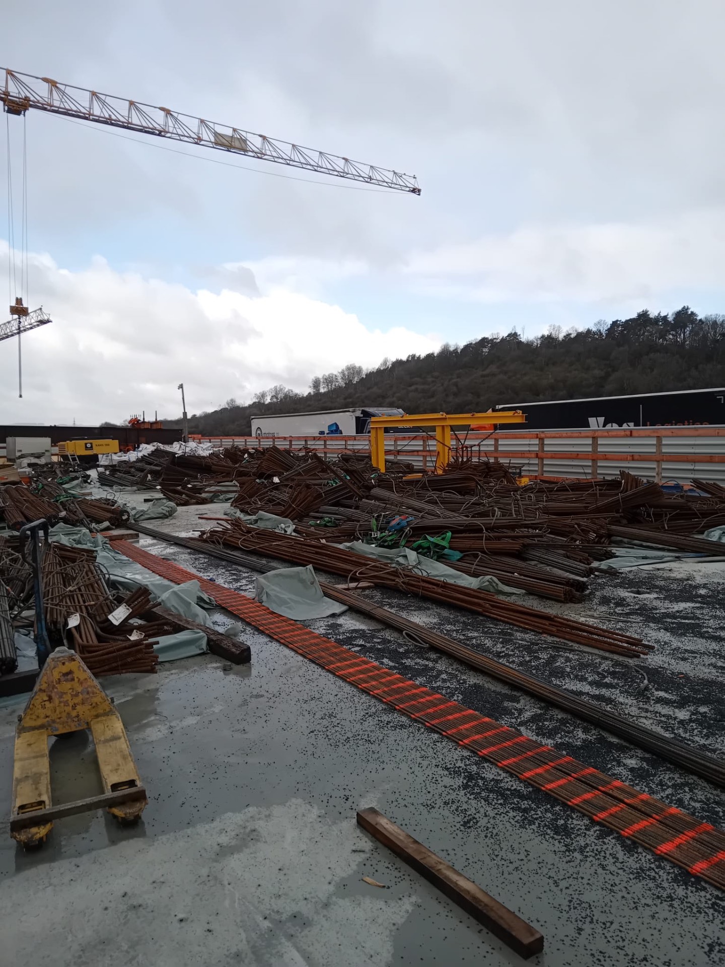 Lagerung von Bewehrungsstahl in Bündeln auf einer Großbaustelle mit Turmdrehkran im Hintergrund
